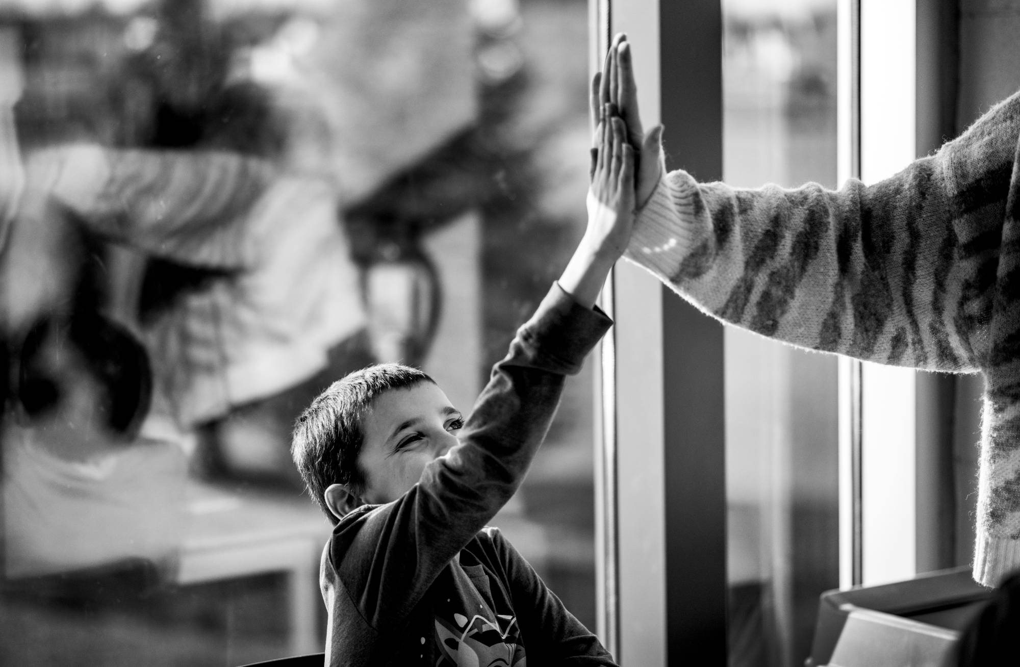 black and white photo of child giving a high five to a teacher outside of the frame